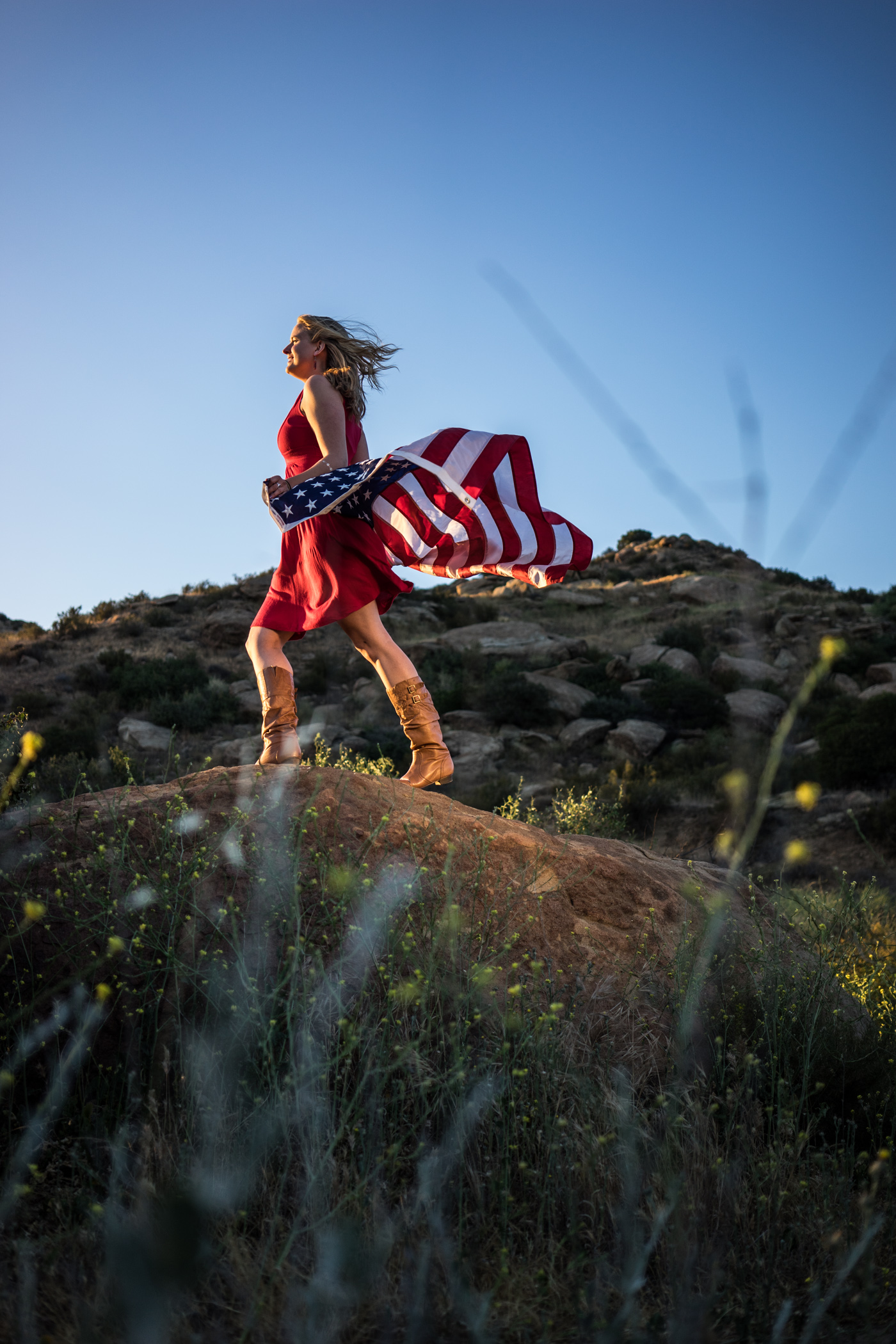 American woman and flag portrait in mountain landscape at sunset